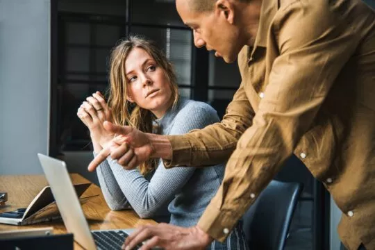 Un homme, probablement un manager, discutant avec sa salariée au regard froid.