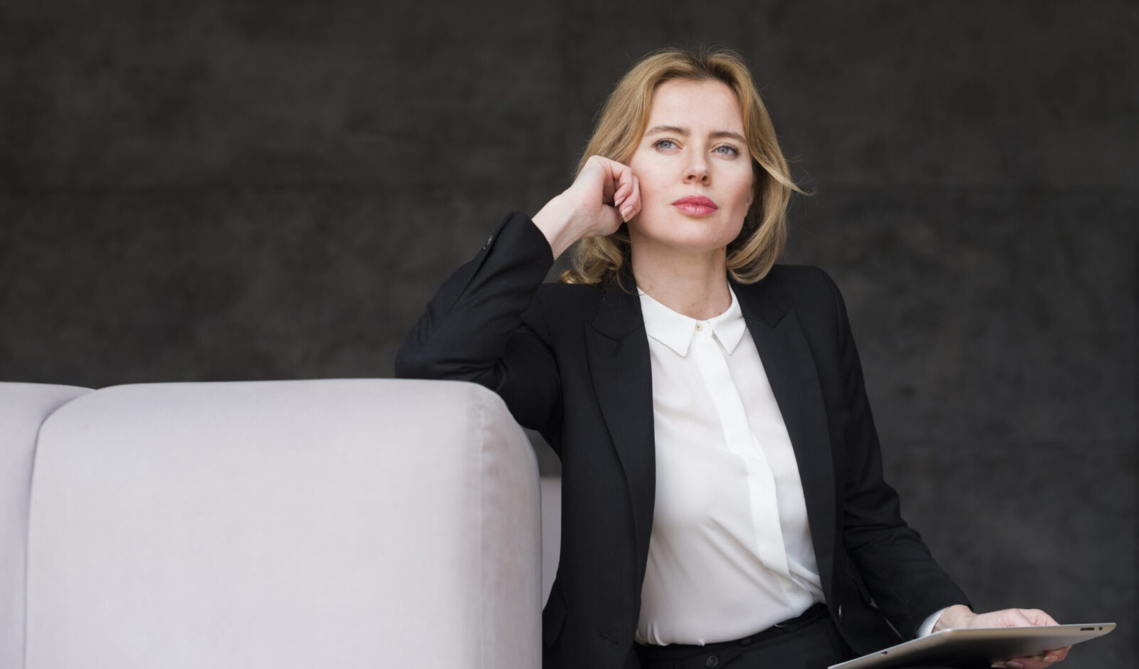 femme d'affaire blonde reflechie avec tablette